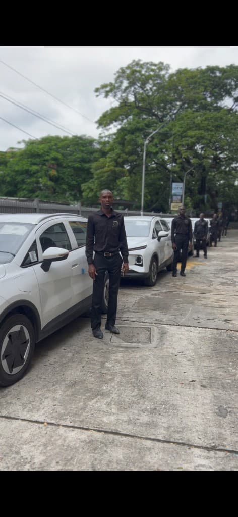 Professional drivers in uniform beside a row of white electric vehicles